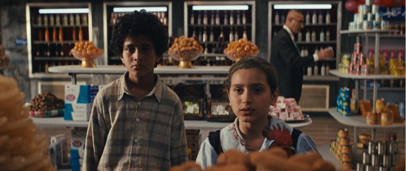 Sajad Mohamad Qasem and Baneen Ahmed Nayyef standing in front of a grocery shop counter in the film The President's Cake.