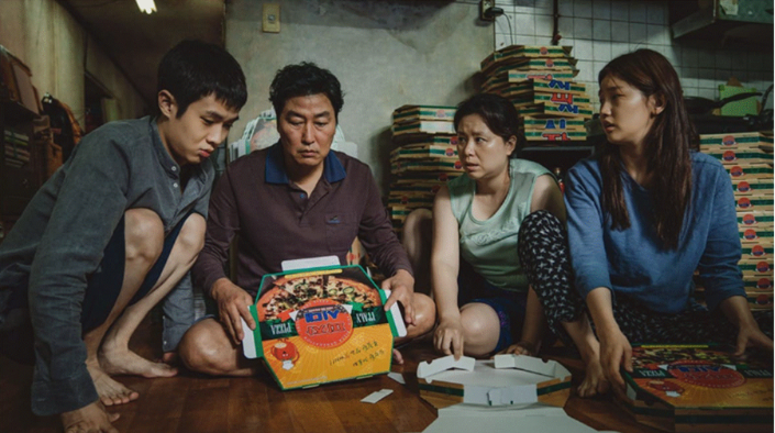 The Kim family folding pizza boxes in their home in the film Parasite.