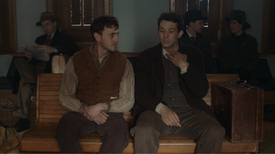 Paul Mescal and Josh O'Connor sitting on a wooden bench wearing period clothing in the film The History of Sound.