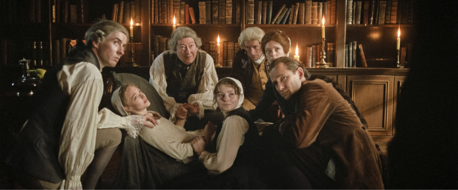 A group of household staff in 18th century England surround a cook, who is lying down in the film The Testament of Ann Lee.
