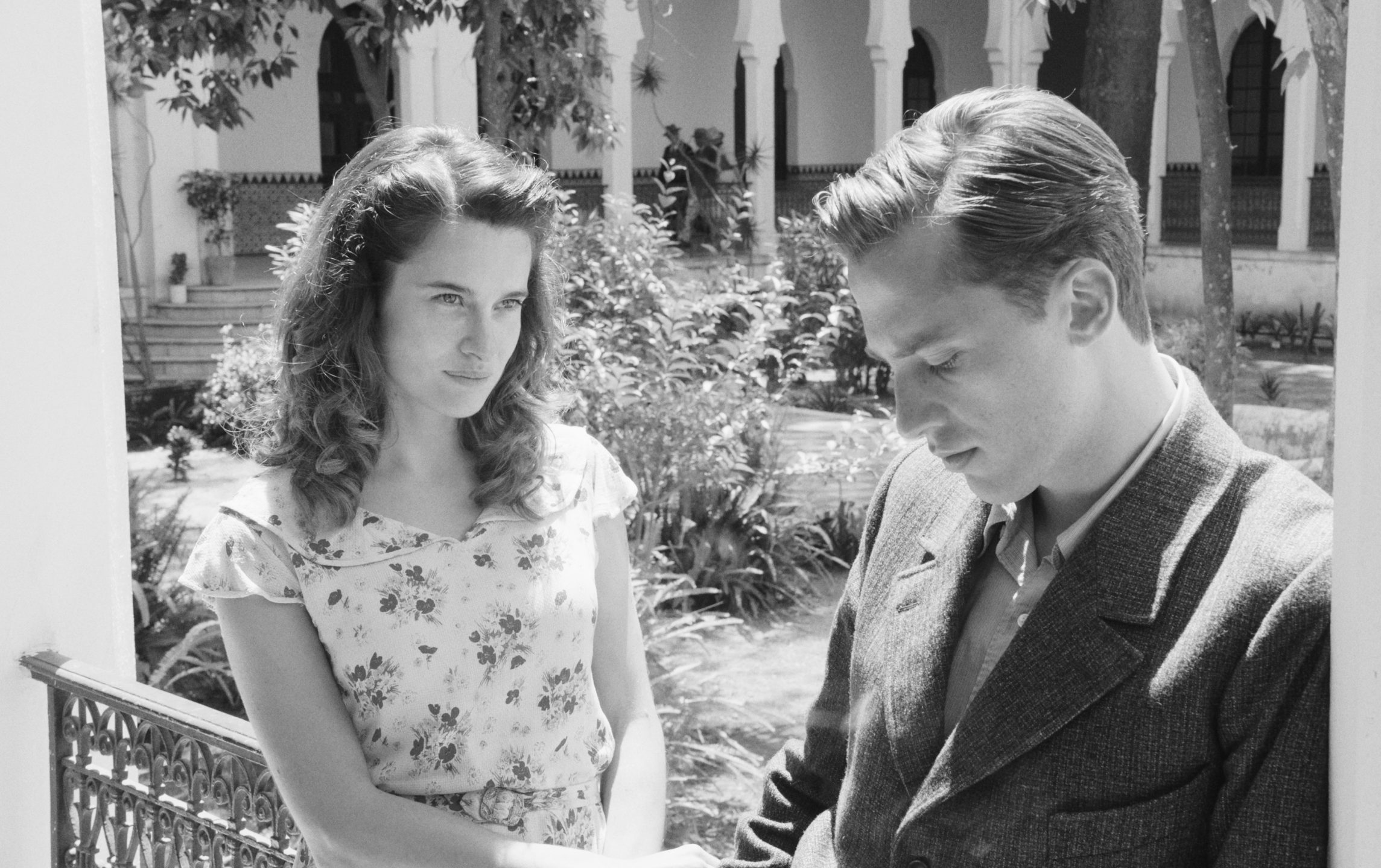 A black and white scene of a well-dressed man and a woman outdoors in the film The Stranger.